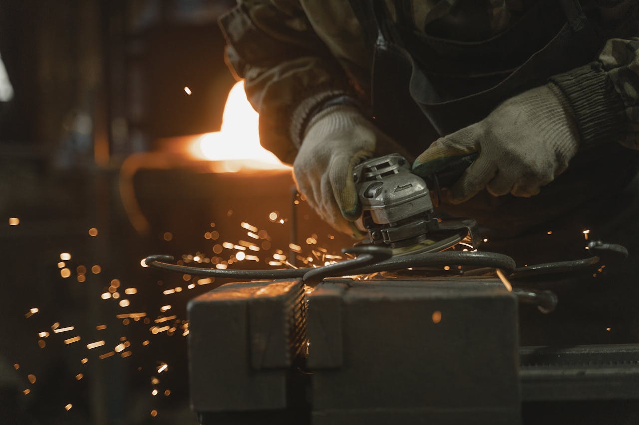 Close-up of a craftsman using an angle grinder on metal. Sparks flying.